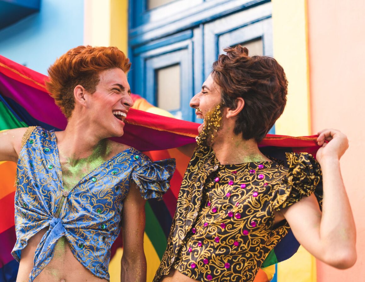 Two men share a rainbow flag at the Pride parade.