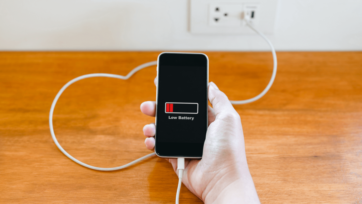 A person plugs in their phone to charge it.
